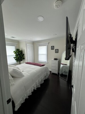 Relax in a serene bedroom with a large bed, potted plant, and mirror.