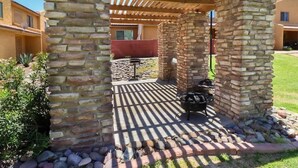 A stone pergola with a grill area, surrounded by a stone wall and a paved patio. - 2BR Condo with patio, Heated Pool, Spa & Gym Access (Phoenix)