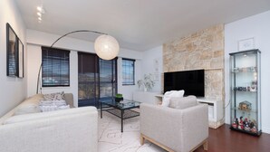 A modern living room with a fireplace, two sofas, a coffee table, and a TV.