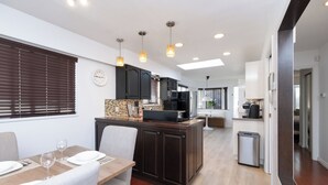 A modern kitchen with dark cabinetry, a central island, and pendant lighting.
