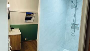 Une salle de bain avec une douche, un lavabo et un meuble en bois.