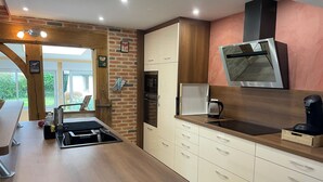 A modern kitchen with a wooden countertop, built-in appliances, and a view of the outdoors. - Villa Normande Piscine Intérieur et Jeux / Proche Honfleur et Deauville (Selles)