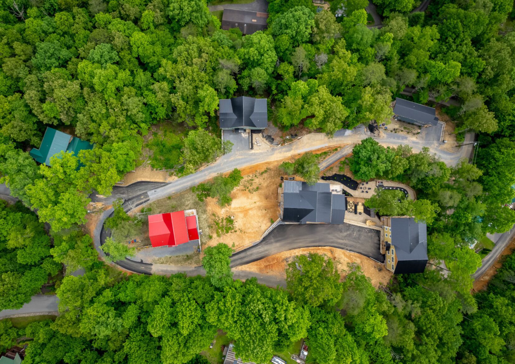 An aerial view of a residential area with multiple houses, roads, and a large open space.