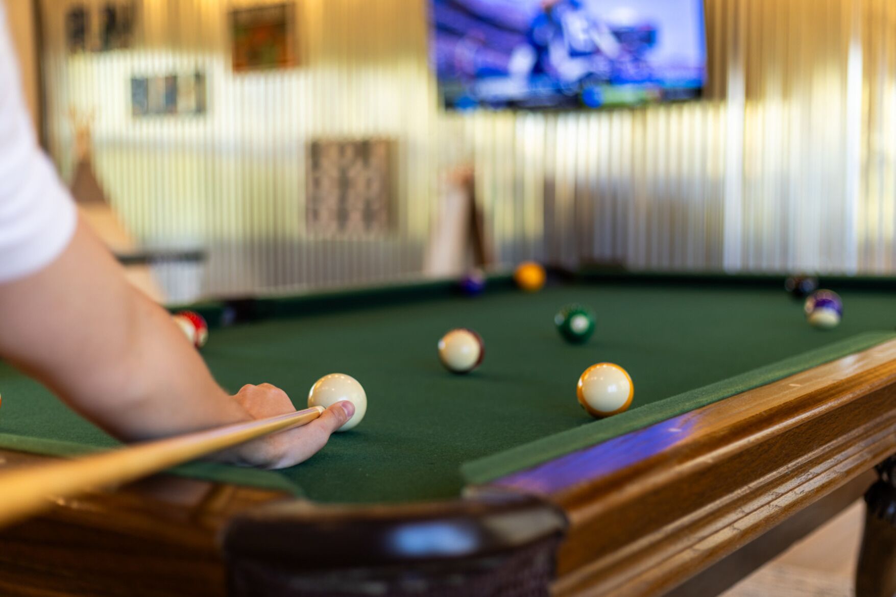 A pool table with balls and a cue stick, indicating a recreational area.