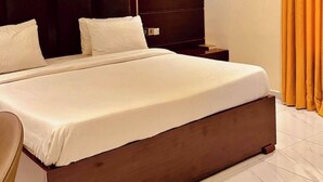 A modern hotel room with a large bed, dark wooden headboard, and a wall-mounted light. - Rosmohr Vintage (Uyo)