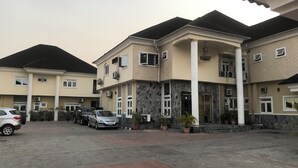 A multi-story residential building with a parking area in front. - Rosmohr Vintage (Uyo)