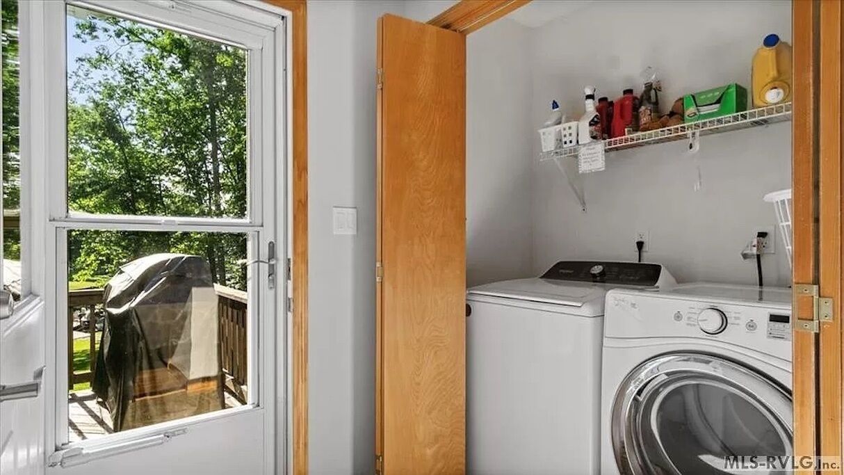 A laundry room with a washing machine, dryer, and wooden shelves with cleaning supplies.
