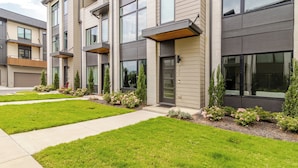 A modern multi-story residential building with a well-maintained lawn and a pathway leading to the entrance. - Southside Retreat with Coffee Bar & Garage (Chattanooga)