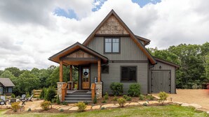 A two-story house with a front porch, a garage, and a landscaped yard. - Soaring Hawk Lodge at Eagles Nest (Elk Park)