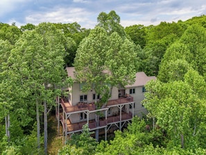 A two-story house surrounded by dense green trees. - Stags Leap at Yonahlossee (Boone)