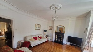 Una sala de estar con un sofá blanco, un sofá estampado, una chimenea y un televisor.
