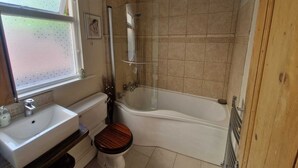 Un baño con bañera, inodoro, lavamanos y ventana con vistas.