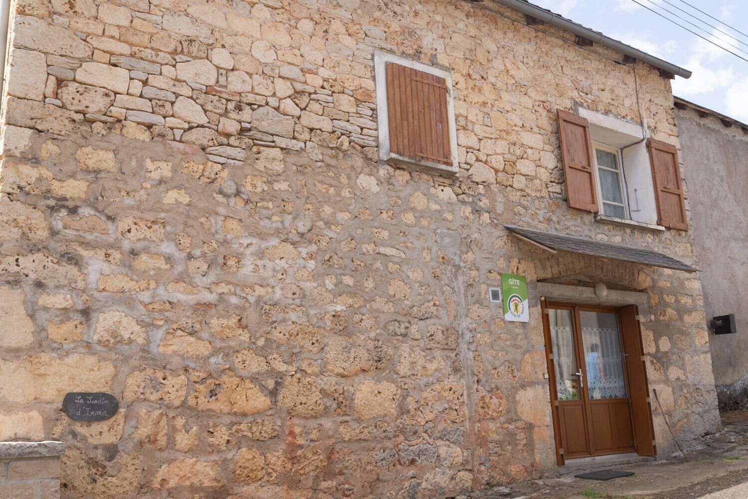Un edificio in pietra con una porta in legno e finestre dotate di persiane.