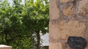 Un mur de pierres sur lequel est apposée une plaque portant l’inscription « Le Jardin d’Herma ».
