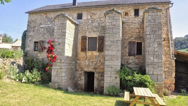A stone building with a rustic exterior, multiple windows, and a small door. - L'Oustal de Julie 3 people (LAVAL DU TARN)