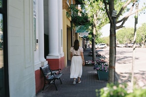 A woman walking on a sidewalk next to a building with a sign that reads 'Gallery by 17'.