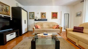 A living room with a sofa, a glass coffee table, a television, and framed artwork on the walls. - Apartment Maria close to the beach and city center (Umag)