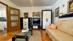 A living room with a glass coffee table, a beige sofa, a TV, and a cabinet. - Apartment Maria close to the beach and city center (Umag)