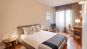 A hotel room with a large bed, a desk, a chair, and a lamp. - VIVA Aliados Spacious & Bright Flat (Porto)