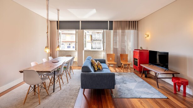 A modern living room with a dining area, a sofa, a TV, and a red cabinet. - VIVA Aliados Spacious & Bright Flat (Porto)