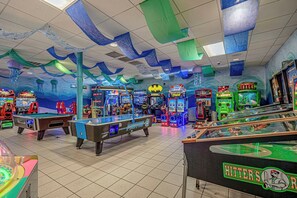 Een indoor speelhal met verschillende spelautomaten, waaronder pooltafels en racegames.