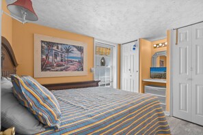 A bedroom with a bed, a painting, a door, and a closet.
