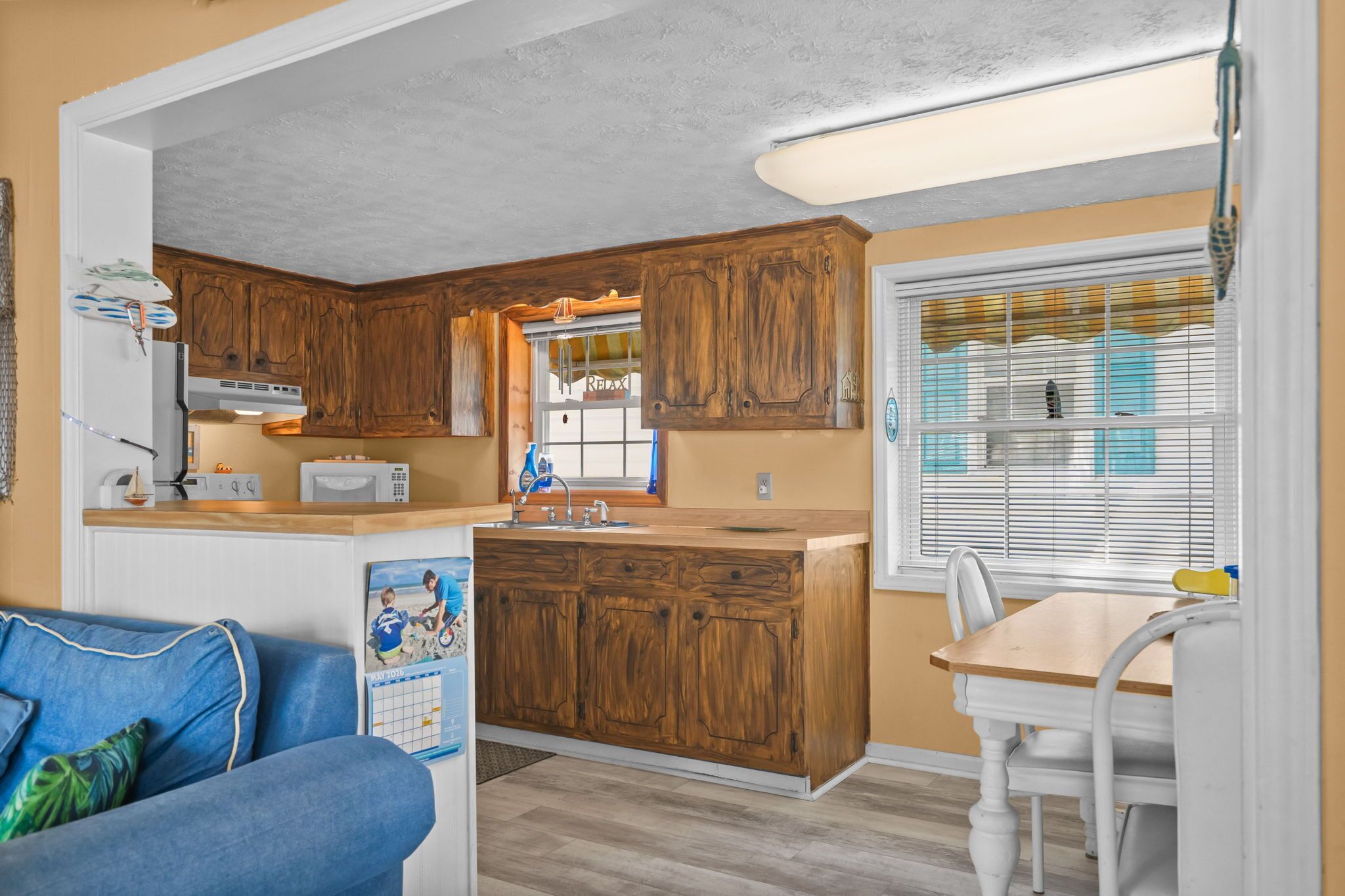 Une cuisine compacte dotée de meubles en bois, d’un réfrigérateur, d’un four à micro-ondes et d’un coin repas avec une table et des chaises.