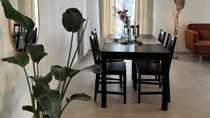 A dining area with a rectangular table, black chairs, and a large potted plant. - Appartement Spacieux et Calme (Bussy-Saint-Georges)