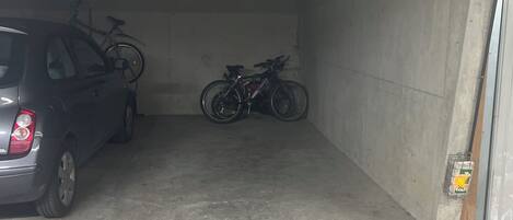 A parking garage with a car and two bicycles parked inside.