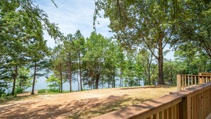 Une terrasse en bois donnant sur un lac, avec des arbres et un ciel dégagé.