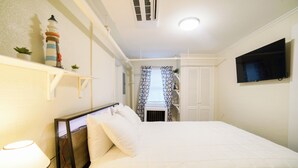 A neatly arranged hotel room with a bed, bedside lamp, and a television mounted on the wall. - Renovated One Bedroom Apartment Downtown Falmouth Minutes From the Beach  (Falmouth)