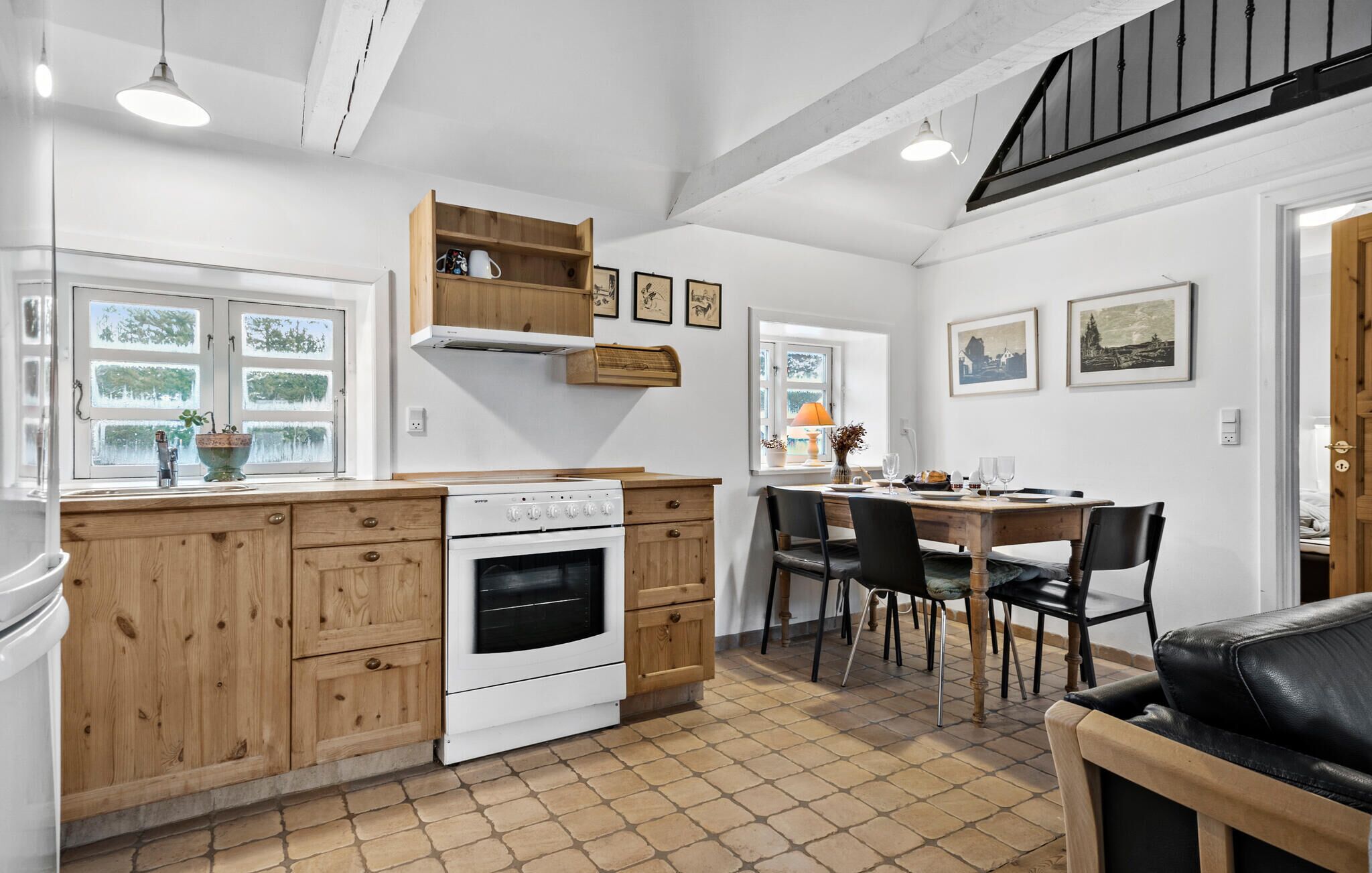A kitchen with wooden cabinets, a stove, and a dining area with chairs and a table.