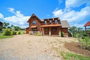 A wooden house with a gravel driveway, a front porch, and a stone foundation. - Timberline at Eagles Nest (Banner Elk)
