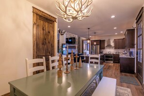 A modern kitchen with dark wooden cabinets, stainless steel appliances, and a stone backsplash. - Timberline at Eagles Nest (Banner Elk)