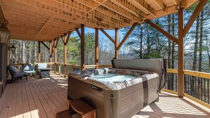 Eine Holzterrasse mit Whirlpool, Liegestühlen und einem Tisch.