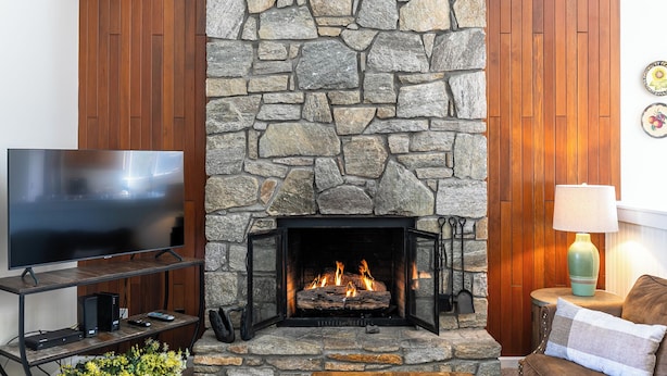 A stone fireplace with a TV on a wooden stand to the left. - Chetola: Chestnut 8 (Blowing Rock)