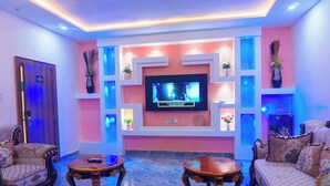 A modern living room with a flat-screen TV, comfortable seating, and decorative vases. - Rolarz Resorts & Hotel (Benin City)