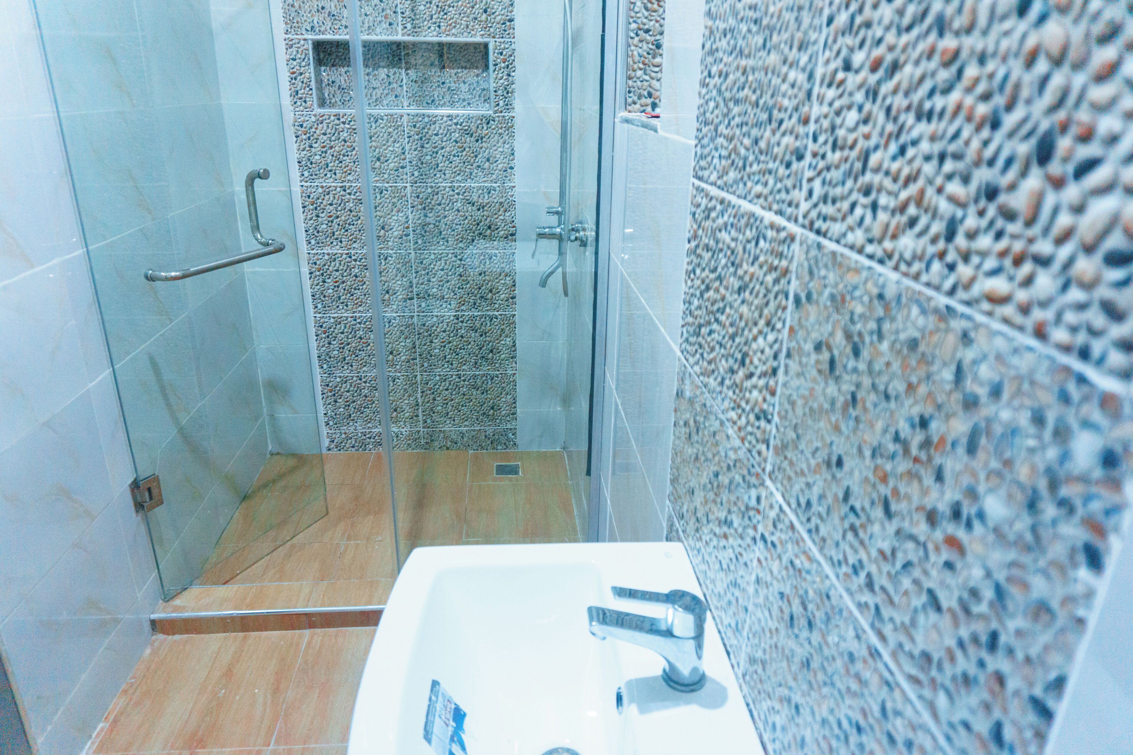 A bathroom with a glass shower enclosure, a sink with a faucet, and tiled walls.
