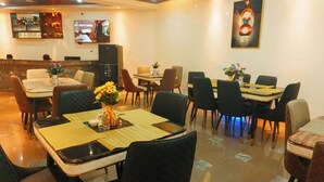 A restaurant with multiple tables and chairs, a bar area with a TV, and a decorative wall piece. - Rolarz Resorts & Hotel (Benin City)