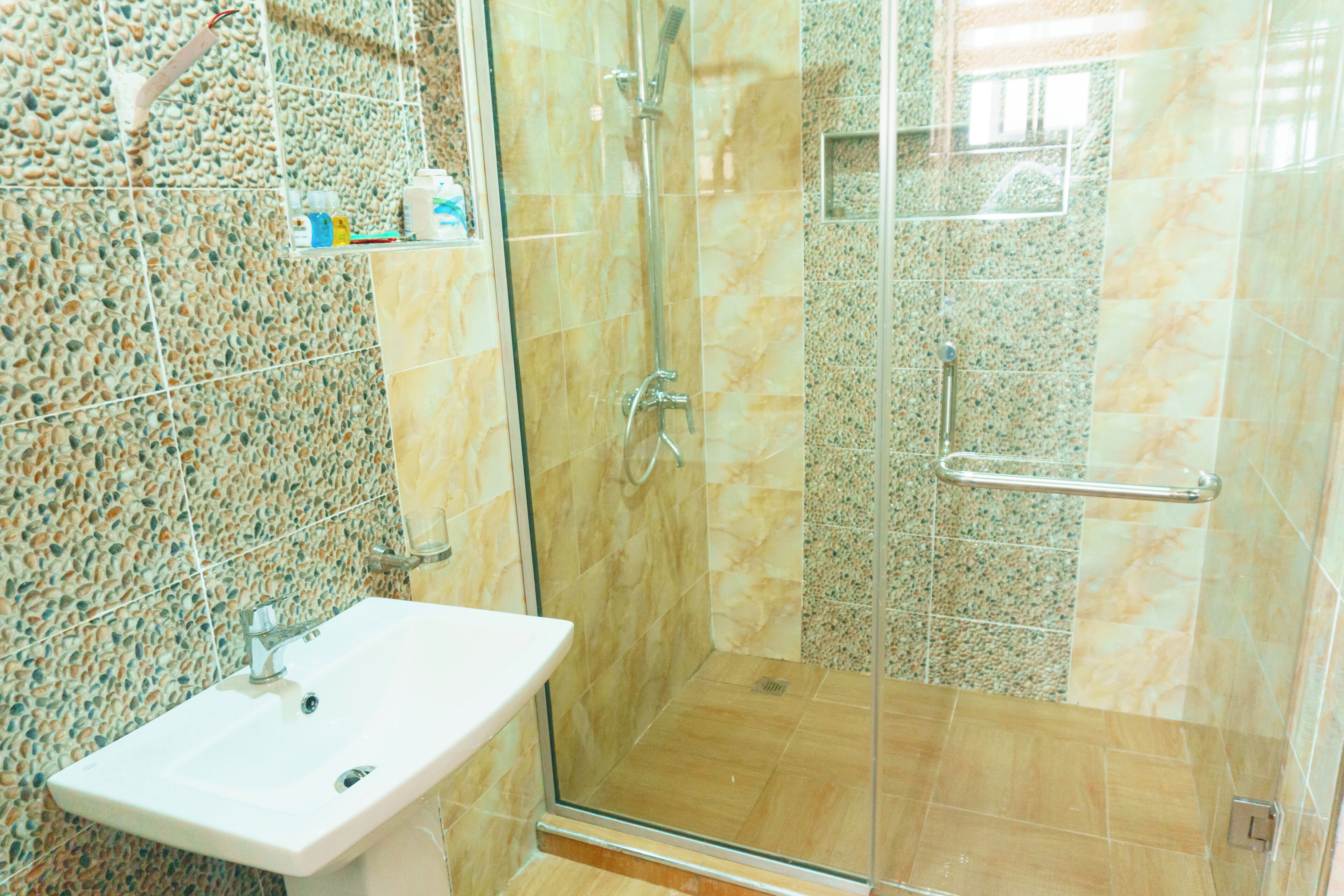 A bathroom with a glass-enclosed shower, a sink, and tiled walls.