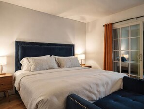 Een keurig opgemaakt slaapkamer met een groot bed, twee nachtkastjes en een raam met gordijnen.