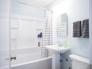 Een badkamer met een badkuip, wastafel, spiegel en handdoeken.