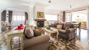 A spacious living room with a fireplace, comfortable seating, and a dining area with a view.