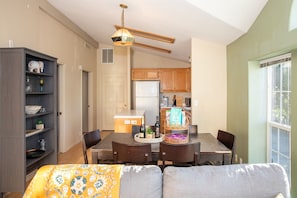 A modern kitchen with wooden cabinets, a dining table with chairs, and a cozy living area with a sofa.