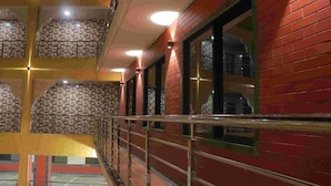 A corridor with tiled walls, a metal railing, and a staircase. - JK Sea Palace (Shrivardhan)