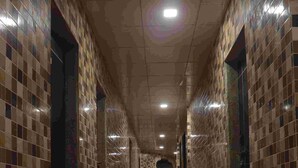 A corridor with tiled walls and a wooden floor, leading to an arched doorway at the end. - JK Sea Palace (Shrivardhan)
