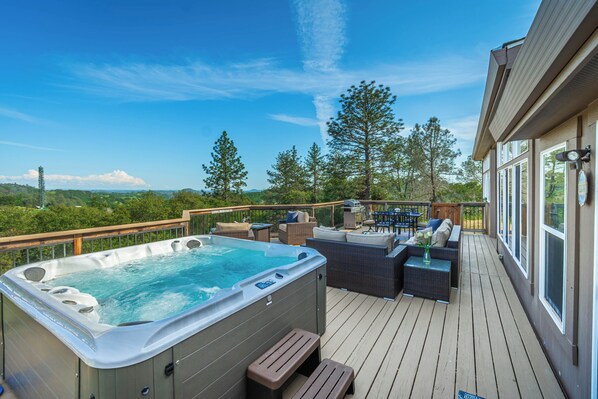 Eine Terrasse mit Whirlpool, Gartenmöbeln und Blick auf die umliegende Landschaft.