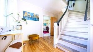 A modern interior with a wooden floor, a staircase with white railings, a desk with a lamp, and a painting on the wall. - Cottage with spectacular views (Ballangen)