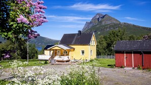 A yellow house with a porch, a red barn, and a mountain in the background. - Cottage with spectacular views (Ballangen)