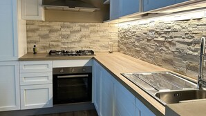 Eine moderne Küche mit Gasherd, Backofen und Spüle aus Edelstahl.